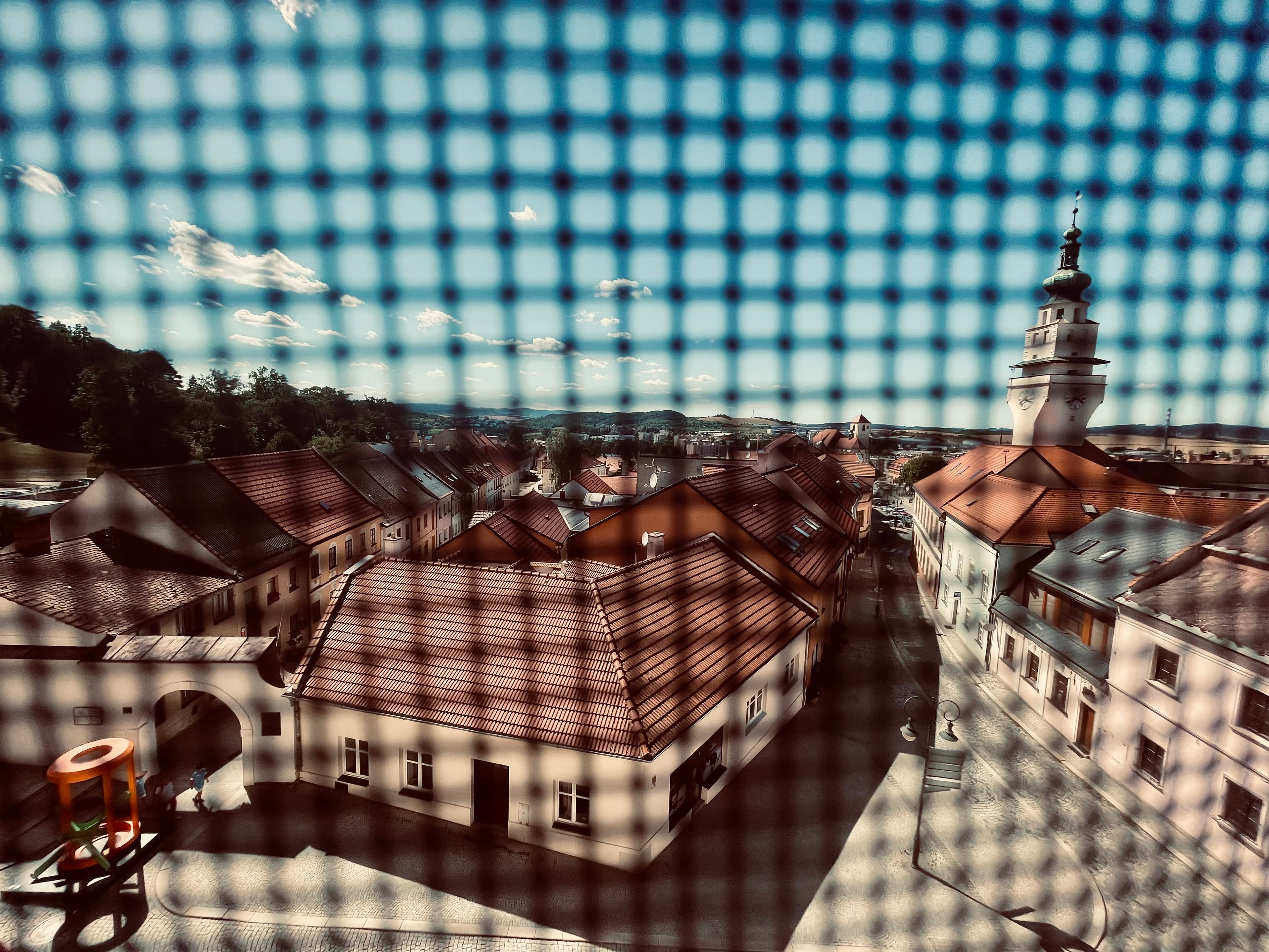 Pohled na střed města přes zasíťované střešní okénko v budově boskovického muzea v rezidenci